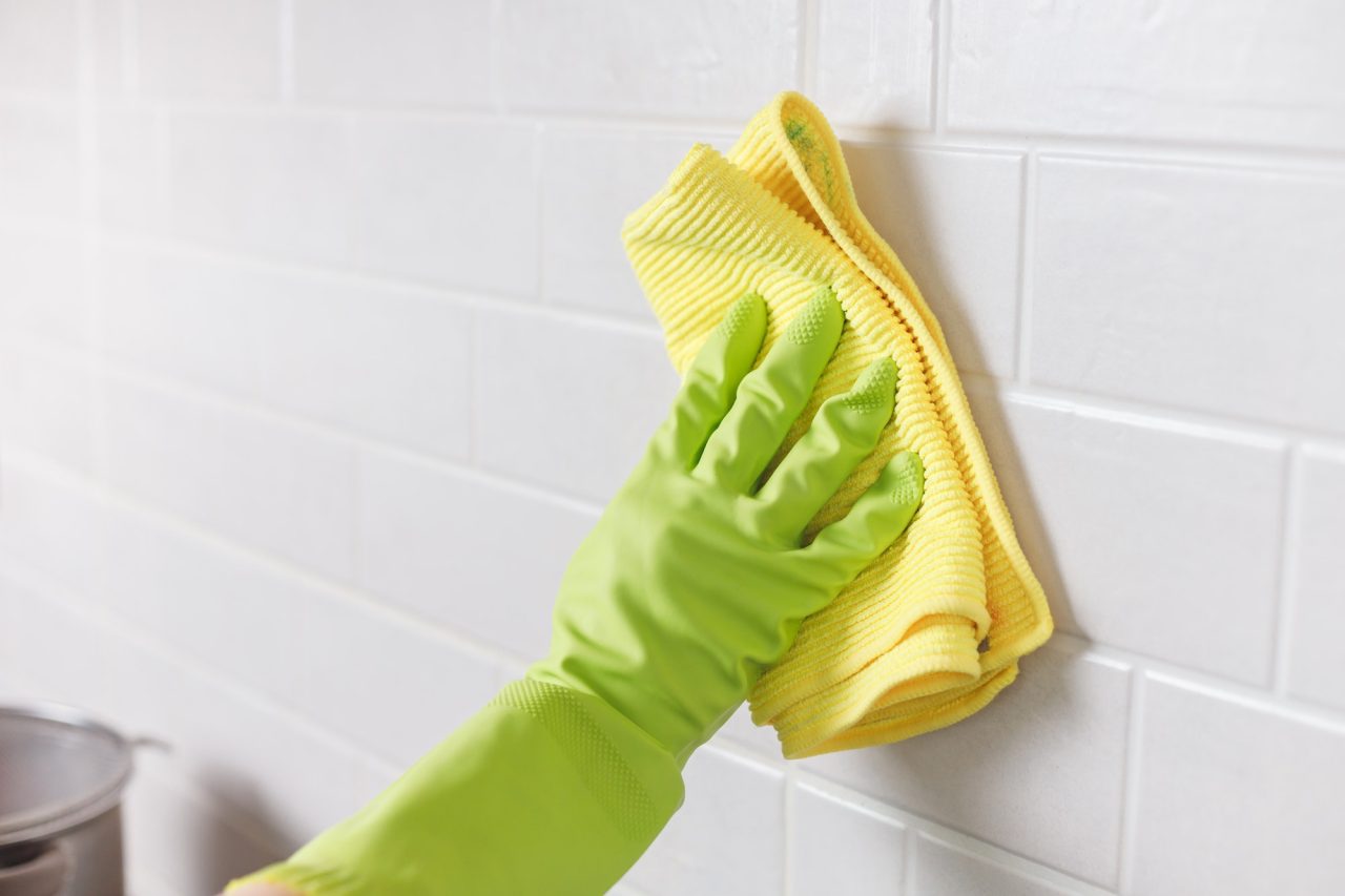 hand-in-gloves-washing-white-tiled-wall-in-kitchen-with-yellow-microfiber.jpg